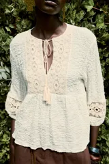 Blusa rústica color crema de cuello redondo con cordón, escote pico y manga larga acabada en elástico. Detalle de tejido combinado en crochet en mangas y parte superior del frente.