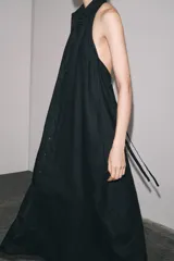 Vestido midi negro de lino, con cuello halter, hombros descubiertos, espalda descubierta, cierre frontal con botones y bajo asimétrico.