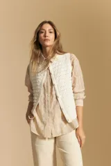 Camisa de manga larga color beige claro con bordado de flores blancas en relieve, cuello clásico y corte holgado.