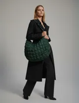 Bolso de hombro acolchado color verde oscuro, con diseño capitoné de rombos y cierre superior con cremallera.