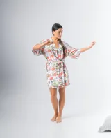 Bata kimono corta de algodón estampado con flores rojas, violetas y verdes. Tiene mangas al codo y lazo de ajuste en la cintura.