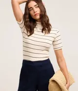 Blusa de ribana color crudo con rayas horizontales azul marino, cuello medio y mangas cortas.