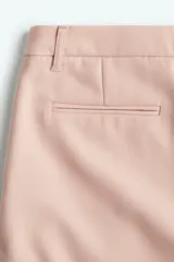 Short de vestir color rosa pálido, de corte recto, con bolsillos laterales y traseros. Se ajusta a la cintura con botón y cierre oculto.