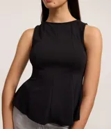 Blusa sin mangas color negro, confeccionada en tejido punto roma, con breteles anchos y corte peplum alargado que se ajusta al cuerpo en el busto y se abre en el ruedo.