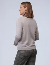 Polera de punto fino marca Nienty, color blanco, con cuello alto volcado y mangas largas con detalle de tajo en los puños.