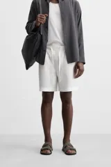 Bermuda regular fit negra confeccionada en tejido de lino. Cintura elástica ajustable con cordón y pliegues frontales. Bolsillos frontales y detalle de bolsillos traseros de plastrón.