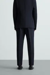 Pantalón de vestir color verde oliva, corte slim fit, con bolsillos laterales y traseros de ojal con botón. Cierre frontal con cremallera y botón.