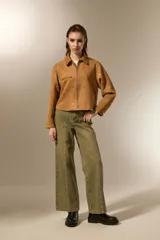 Campera cropped color camel de poliéster, con cuello camisero, cierre frontal y un bolsillo con cierre en el pecho. Está decorada con tachas plateadas distribuidas por toda la prenda.