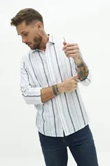 Camisa de manga larga para hombre, color blanco con rayas verticales finas en tonos grises y azules. Confeccionada en una mezcla de lino y algodón, de corte semi slim y logo bordado en el pecho.