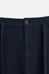 Pantalón azul marino de corte recto, confeccionado en tejido de algodón y lino. Tiene cintura elástica ajustable con cordón, bolsillos delanteros y traseros de vivo. Cierre frontal con cremallera y botón.