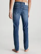 Jeans de denim elástico azul con efecto lavado, corte skinny, tiro bajo, cinco bolsillos y cierre con cremallera.