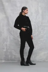 Pantalón de pana negro, corte slim, con cintura alta y cierre frontal con botón y cremallera.