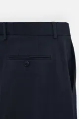Pantalón de vestir azul marino, de corte recto, con pinzas frontales, bolsillos laterales y traseros con doble vivo y botón.