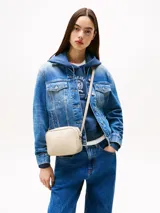 Bandolera Tommy Jeans color crema, de forma rectangular y correa ajustable. Presenta el logo de la marca en relieve en el frente.