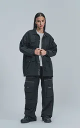 Campera negra oversize con broches en el delantero, forrada con red, múltiples bolsillos con detalles en réflex y puños elásticos en las mangas.