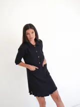 Vestido camisero verde seco de corte holgado, con cuello camisero, mangas 3/4 y cierre frontal con botones.