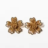 Par de aros colgantes con forma de flor, con centro tejido en color marrón y contorno dorado.
