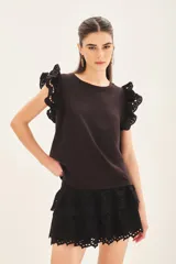 Remera negra de jersey de algodón con calce recto, escote redondo y doble volado de broderie en mangas.