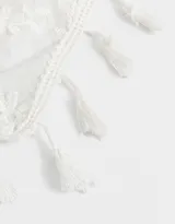 Vincha tipo bandana de tela blanca con bordado de flores y terminaciones con borlas. Se ata con lazos.