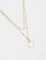 Collar corto dorado de doble cadena, una con perlas y otra con bolitas doradas. Dije de corazón transparente.