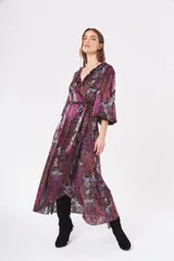Vestido largo con estampado floral en tonos fucsia, rojo, blanco y negro. Diseño cruzado con volantes en el escote y mangas largas abullonadas.