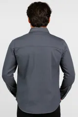 Camisa manga larga color verde militar, con cuello clásico, cierre frontal con botones a tono, dos bolsillos de parche con botón en el pecho y puños abotonados.