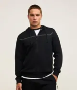 Campera deportiva negra texturizada, con capucha y cierre frontal. Tiene detalle de raya reflectante en el pecho y bolsillos con cierre.