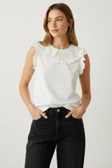 Musculosa blanca sin mangas de rayon con broderie, volados y cuello redondo.
