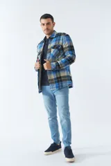 Sobrecamisa de algodón para hombre con interior de corderito, estampado a cuadros en tonos negro, blanco y azul. Tiene cierre de botones, bolsillos tipo cartera y logo en goma. El modelo usa talle M.