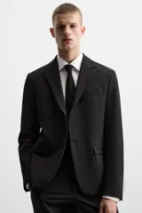 Blazer slim fit negra confeccionada en tejido con viscosa. Cuello con solapas de muesca, manga larga con puño con detalle de botones, bolsillo de vivo en pecho y de solapa en cadera, bolsillo interior, bajo con aberturas en espalda y cierre frontal con botones.