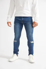 Jean skinny de hombre color negro, ajustado desde la cadera hasta los tobillos, con roturas en las rodillas y logo bordado en el bolsillo trasero.