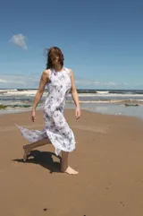 Vestido midi sin mangas con estampado floral azul sobre fondo blanco, tajos laterales y cierre con botón en la espalda.