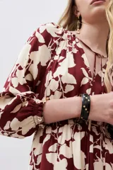 Pulsera rígida negra con puntos dorados.