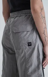 Bermuda cargo color gris oscuro (carbón), de corte recto y largo hasta la rodilla, con cinturón de cinta negra ajustable con hebilla de plástico. Presenta bolsillos laterales y bolsillos cargo con solapa en las piernas.