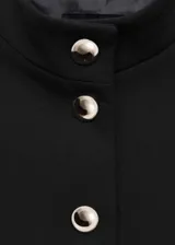 Chaqueta negra entallada con cuello mao y cierre frontal con botones plateados.