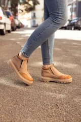Bota de cuero color beige con puntera marrón, cierre frontal con cremallera y suela track.