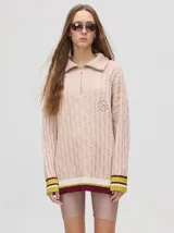 Sweater tejido de algodón color rosa claro, con cuello polo con cierre de cremallera, mangas largas con puños a rayas de colores y diseño de ochos.