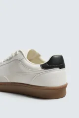 Zapatillas deportivas de hombre, de estilo retro, color blanco con puntera de gamuza color crema, detalle trasero en cuero negro y suela marrón.