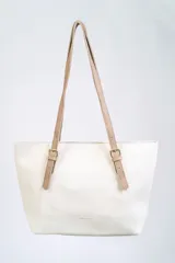 Bolso tipo tote color blanco con textura símil cuero y doble asa de hombro color beige con hebillas doradas.