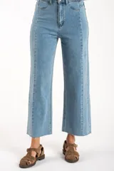 Jean de mezclilla azul claro, tiro medio, corte recto con leve campana al tobillo. Presenta costuras verticales marcadas en el frente y en los laterales de las piernas, y terminación deshilachada en el ruedo.