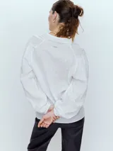 Camisa blanca con textura sutil y manga larga, diseño clásico y botones frontales.