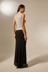 Falda larga negra con detalle de nudo lateral y tiras colgantes, de corte ajustado en la parte superior y ligeramente acampanado en el ruedo.
