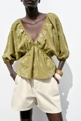 Top amarillo con estampado floral en jacquard, escote en pico, mangas cortas abullonadas con elástico, cintura elástica y espalda descubierta ajustable con lazos.