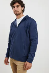 Cardigan de tejido de punto color azul piedra melange, con cuello redondo, cierre frontal completo y bolsillos laterales.