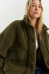 Campera de sherpa verde, con cierre frontal y bolsillos laterales, de corte holgado.