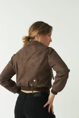 Campera corta color marrón chocolate, con textura tipo gamuza, cuello clásico, cierre frontal asimétrico con cremallera metálica y bolsillos laterales con cremallera.