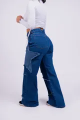 Pantalón de jean azul con parches en forma de estrella de un tono más claro y bordes desflecados.