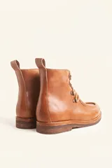 Bota de cuero vacuno color bordó con acabado brillante, diseño tipo botineta con cordones y ganchos metálicos. Presenta suela de goma tipo crepe con plataforma y costuras visibles en la puntera.