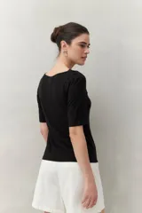 Remera negra de modal de manga corta con cuello asimétrico y detalle de nudo con frunces.