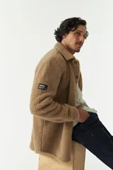 Sobrecamisa de sherpa color marrón claro con cuello camisero, cierre frontal con botones, bolsillo tipo parche en el pecho y manga larga.